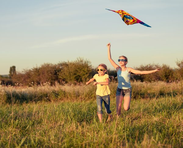 Happy children playing on the field at the day time. Concept of friendly siblings of family.